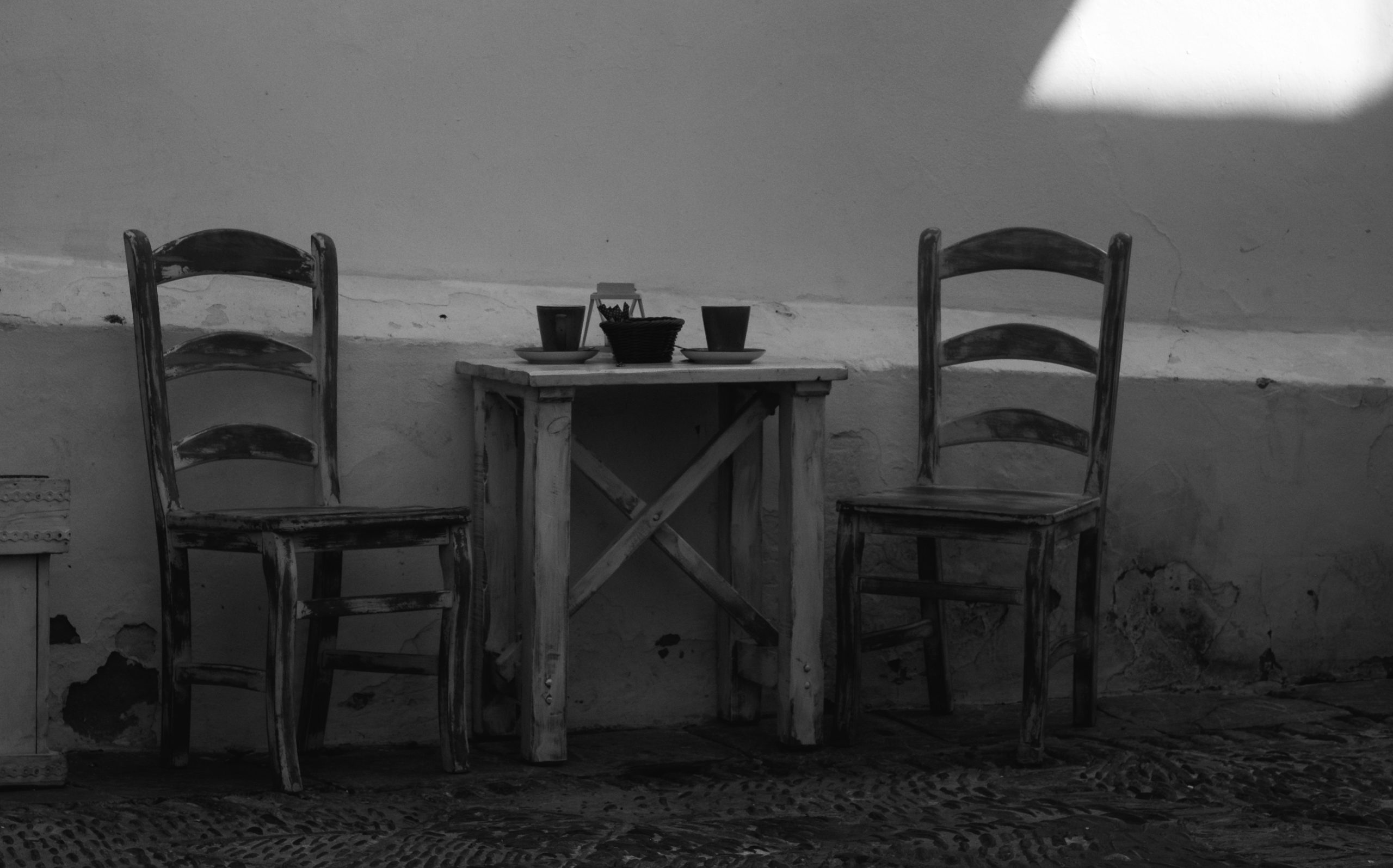 Two chairs at a small table set for two by Emiliano Cicero